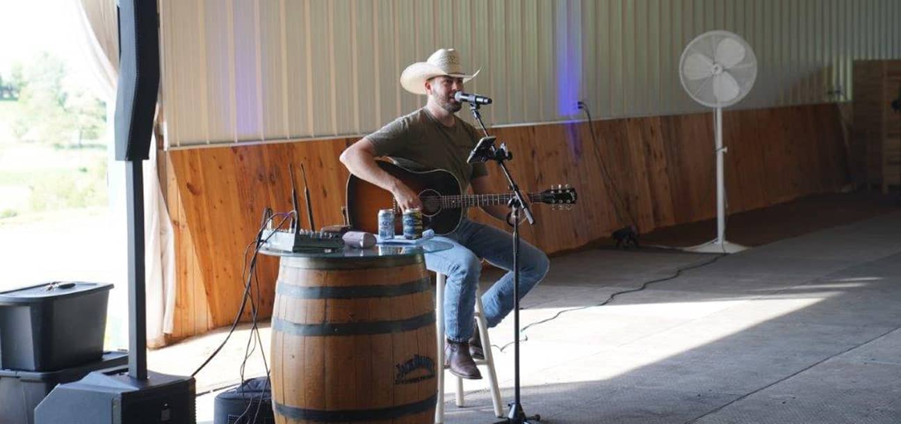 Musician wearing a cowboy hat singing and playing the guitar